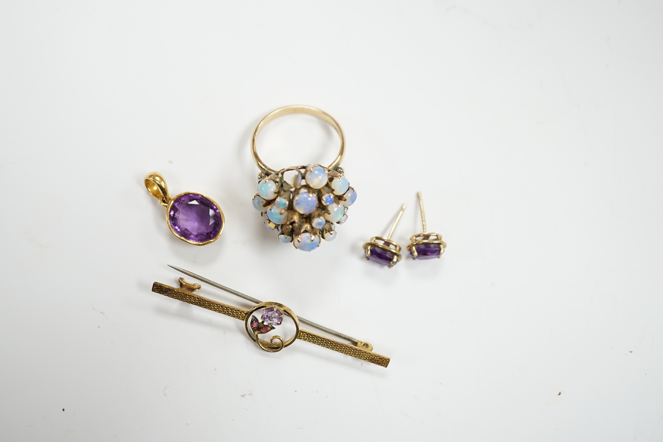 A cased 9ct, three stone amethyst and ruby set bar brooch, 49mm, a 14k and opal cluster set dress ring, a yellow metal and amethyst set pendant and a pair of similar ear studs.